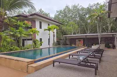 a swimming pool with benches next to a house at Nongthale Mountain View in Klong Muang Beach