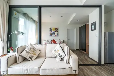a living room with a white couch and a large mirror at The Deck Condominium by Lofty in Patong Beach