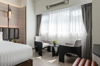 a hotel room with a bed and chairs and a window at Panmanee Hotel-Newly Renovated in Phi Phi Don