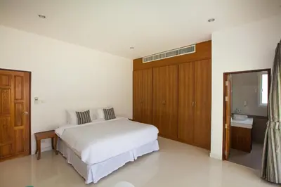 a bedroom with a white bed and wooden cabinets at Baan Anna in Ao Nang Beach