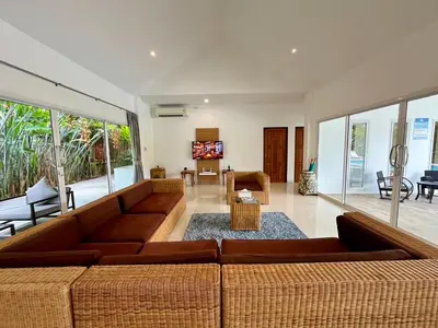 a living room with a brown couch and a living room withwindows at Baan Anna in Ao Nang Beach