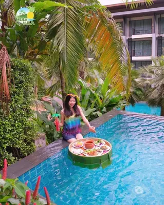 a girl is sitting in a pool with a pizza in the water at HULA HULA RESORT l truly tropical and fun wellness in Ao Nang Beach