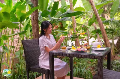 a woman sitting at a table with a plate of food at HULA HULA RESORT l truly tropical and fun wellness in Ao Nang Beach