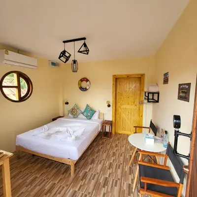 a bedroom with a bed and a table and a window at Namphung Phuket Boutique Resort in Rawai Beach
