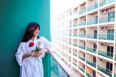 a woman standing on a balcony holding flowers at Sun Sea Sand Patong in Patong Beach