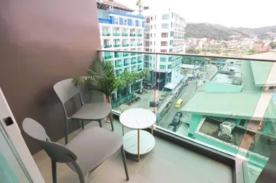 a balcony with chairs and tables and a view of a city at Sun Sea Sand Patong in Patong Beach