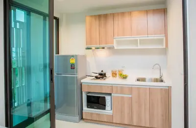 a kitchen with wooden cabinets and a stainless steel refrigerator at Connext Residence Phuket in Phuket Town