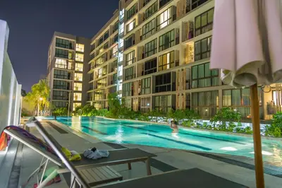 a person in a swimming pool next to a building at Connext Residence Phuket in Phuket Town