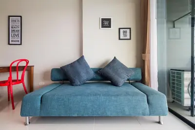 a blue couch in a living room with a red chair at Apartments at The Bliss Condo by Lofty in Patong Beach