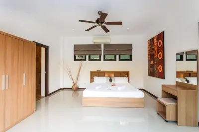 a bedroom with a bed and a ceiling fan at Frangipani pool villa - garden, BBQ & maid in Nai Harn Beach