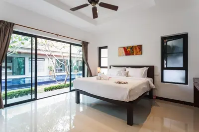a bedroom with a bed and a large window at Frangipani pool villa - garden, BBQ & maid in Nai Harn Beach