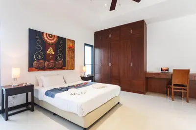 a bedroom with a bed with a painting on the wall at Frangipani pool villa - garden, BBQ & maid in Nai Harn Beach