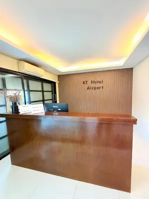 a reception desk at a hotel with a sign on the wall at KT Hotel Airport in Nai Yang Beach