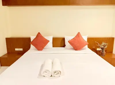 a bedroom with a white bed with orange and white pillows at KT Hotel Airport in Nai Yang Beach