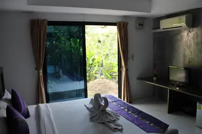 a room with a bed and a window and a television at B Happy Resort - SHA ExtraPlus in Kamala Beach