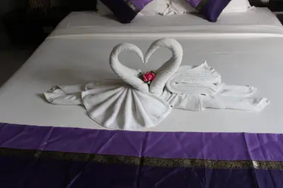 two swans made out of towels on a bed at B Happy Resort - SHA ExtraPlus in Kamala Beach