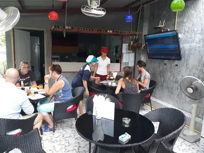 a group of people sitting at tables in a restaurant at B Happy Resort - SHA ExtraPlus in Kamala Beach