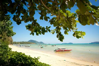 a beach with boats and people in the water at The Title by Eeri in Rawai Beach