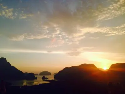 a sunset over the ocean with rocks in the water at Lantala Residence in Natai Beach
