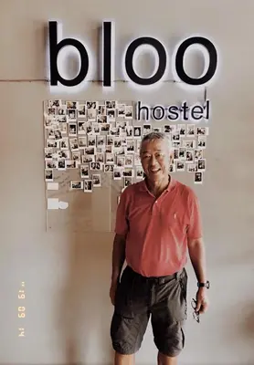 a man standing in front of a wall with a sign at Bloo Hostel in Phuket Town
