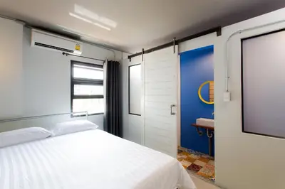 a bedroom with a white bed and a tv at Bloo Hostel in Phuket Town