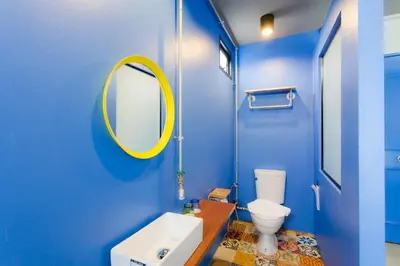 a blue bathroom with a white toilet and a mirror at Bloo Hostel in Phuket Town