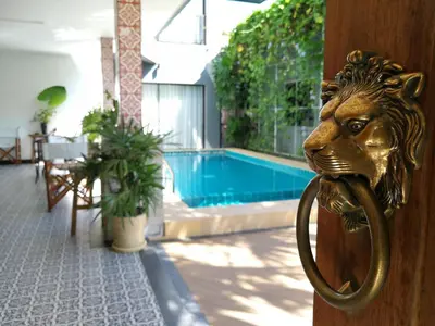 a gold lion door knocker on a door with a pool at The Umbrella House in Kamala Beach