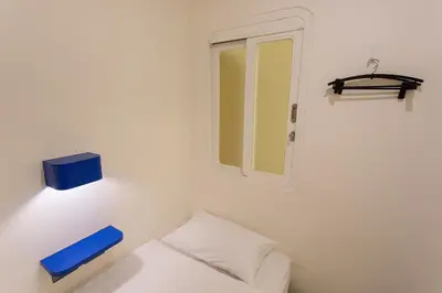 a small white room with a mirror and a bed at BearPacker Patong Hostel in Patong Beach