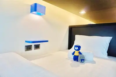 a white bed with a blue toy sitting on a pillow at BearPacker Patong Hostel in Patong Beach