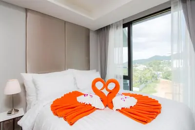 two towels in the shape of two swans on a bed at 6th Avenue Surin Beach - Official Account in Surin Beach