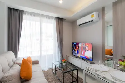 a living room with a white couch and a tv at 6th Avenue Surin Beach - Official Account in Surin Beach