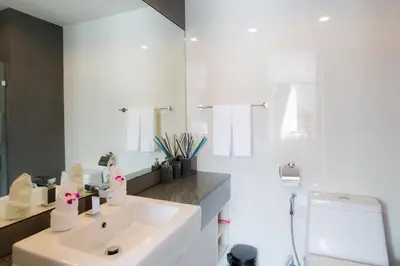 a white bathroom with a sink and a mirror at 6th Avenue Surin Beach - Official Account in Surin Beach