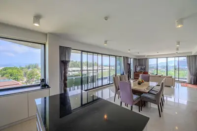 a living room with a table and chairs and large windows at 6th Avenue Surin Beach - Official Account in Surin Beach