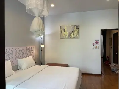 a bedroom with a large white bed and a chandelier at Nawaporn Place in Phuket Town