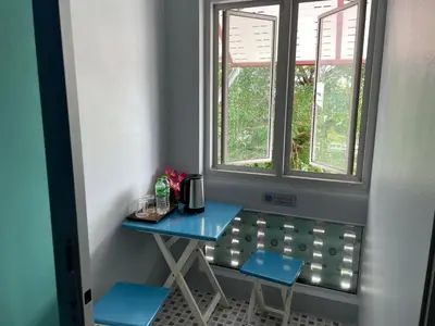 a small table and two stools in front of a window at Nawaporn Place in Phuket Town