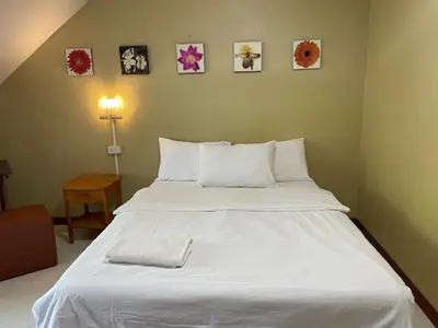a large white bed in a bedroom with pictures on the wall at Nawaporn Place in Phuket Town