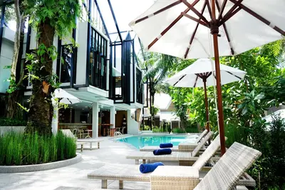 a pool with chairs and umbrellas next to a building at Deevana Krabi Resort in Ao Nang Beach