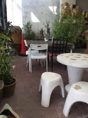 a patio with white tables and chairs and plants at The Duck in Phuket Town