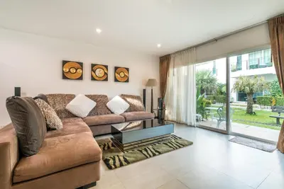 a living room with a couch and a large window at AP Grand Residence by Lofty in Kamala Beach