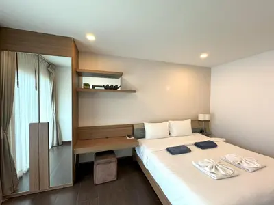a bedroom with a bed with a desk and a window at AP Grand Residence by Lofty in Kamala Beach