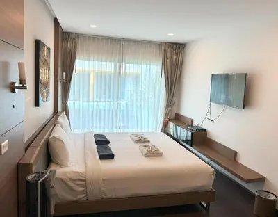 a bedroom with a large bed with a window at AP Grand Residence by Lofty in Kamala Beach