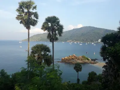 a view of a bay with palm trees and boats at Rawai Condotel 3 in Rawai Beach