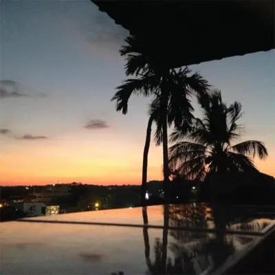 two palm trees on top of a swimming pool at sunset at Rawai Condotel 3 in Rawai Beach