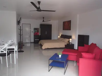 a living room with a bed and a red couch at Coconoi Residence in Nai Harn Beach