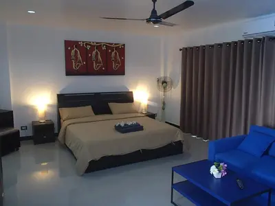 a bedroom with a bed and a blue couch at Coconoi Residence in Nai Harn Beach