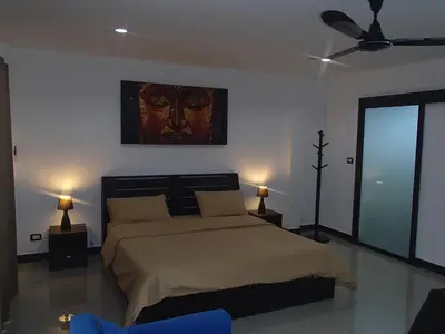 a bedroom with a bed with a painting on the wall at Coconoi Residence in Nai Harn Beach