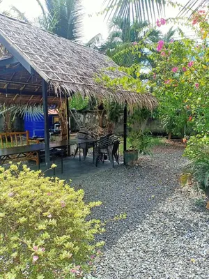 a patio with a table and chairs and a thatch roof at Coconoi Residence in Nai Harn Beach