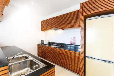 a kitchen with a sink and a refrigerator at The Quarter by Lofty in Surin Beach