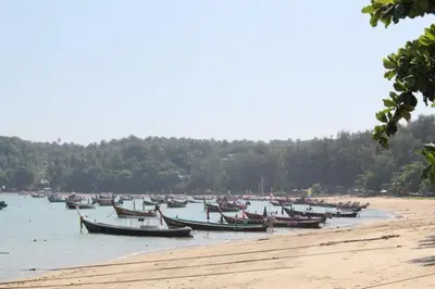 a group of boats sitting in the water on a beach at The Title Comfort Condotel in Rawai Beach