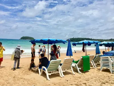 a group of people sitting on a beach with umbrellas at Casa E Mare in Kata Beach